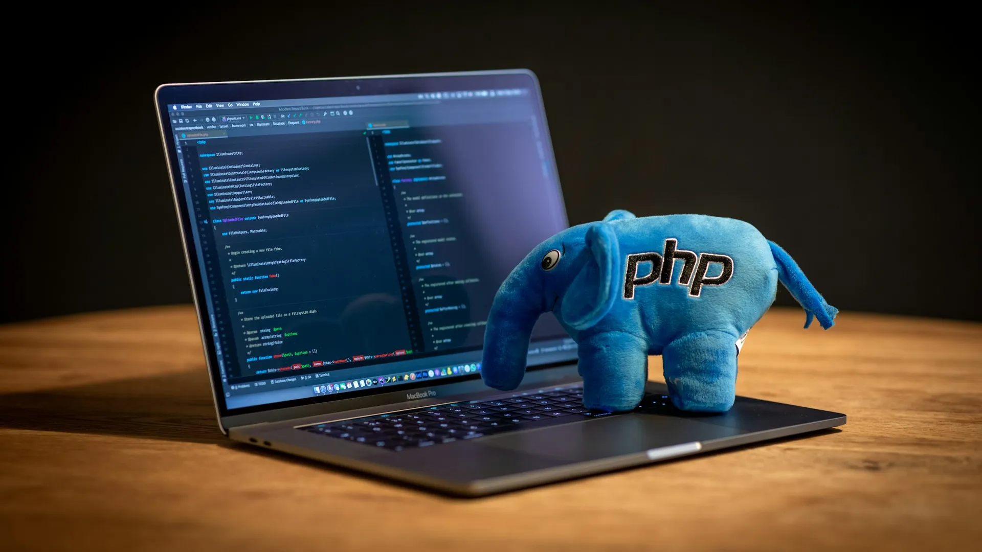 A laptop showing PHP code. On top of laptop's keyboard is a stuffed toy of PHP's mascot.