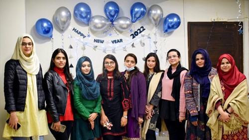 A group of ladies is standing under decorations for a new year celebration.